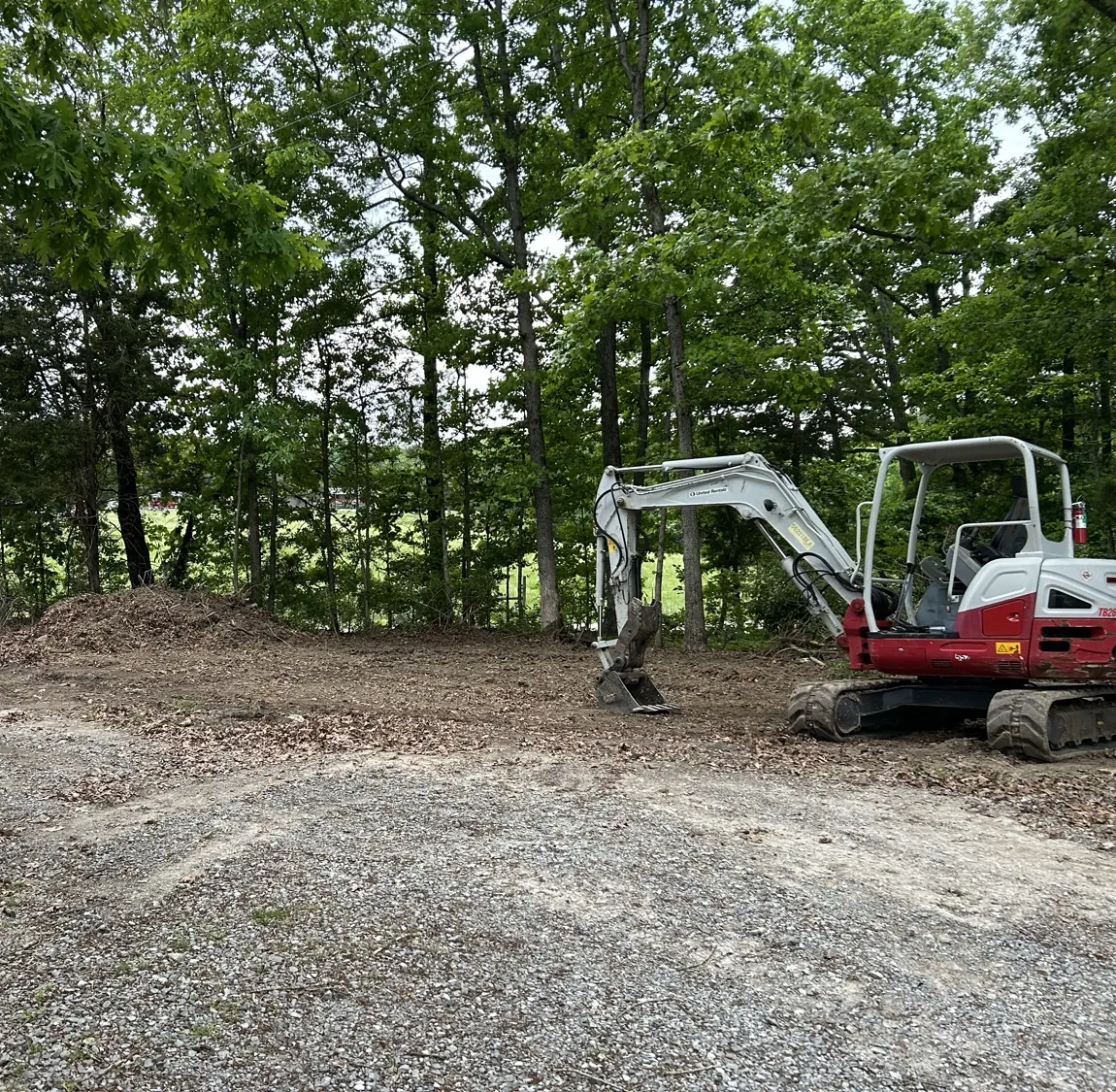 A cleared, level building pad with a mini excavator