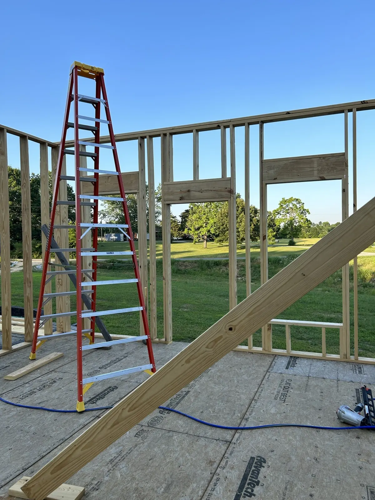 Wood wall framing on an OSB subfloor with a red step ladder